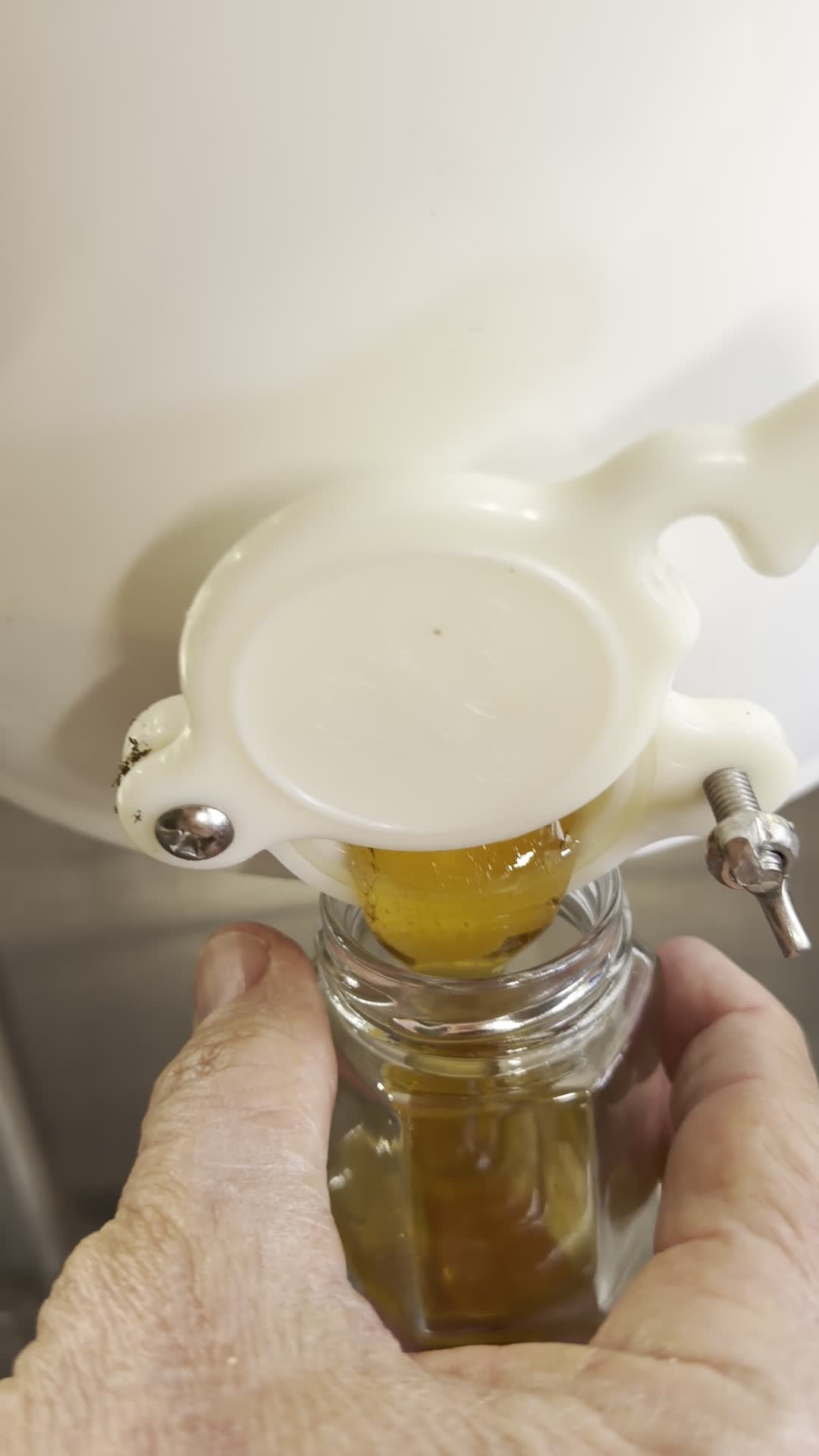 Honey flowing from bucket into a jar